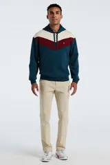 Hoodie de corte regular con diseño de bloques de color en azul petróleo, bordó y beige. Presenta capucha con cordones ajustables, bolsillo tipo canguro frontal y puños y ruedo acanalados. Incluye un pequeño logo bordado en el pecho.