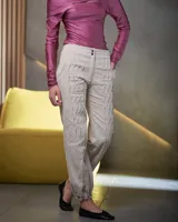 Pantalón babucha color beige de algodón, con corte a la cintura y piernas levemente amplias. Presenta textura de tablitas centrales y elásticos con broches inferiores que ajustan las piernas al tobillo.