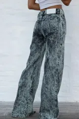 Jean de mujer de corte acampanado, tiro alto, color gris con efecto acid wash. Presenta costuras verticales en la parte delantera y bolsillos de parche.