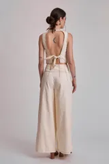 Pantalón marrón de corte palazzo, tiro alto, con pliegues frontales y pespuntes blancos decorativos.