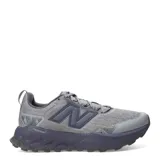 Championes de trail running New Balance modelo Garoe, en color gris con suela y detalles en azul marino. Confeccionados con capellada de malla transpirable y refuerzos sintéticos, cuentan con entresuela con tecnología Fresh Foam y suela con tacos para mayor tracción en terrenos difíciles.