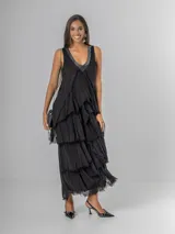 Vestido largo negro de seda con escote en V adornado con lentejuelas plateadas. Presenta un diseño de capas superpuestas con terminaciones deshilachadas que aportan volumen y movimiento. Es de corte sin mangas con breteles anchos y espalda elastizada.