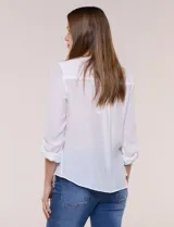 Blusa de calce relajado color salmón, confeccionada en tela liviana con textura sutil. Presenta escote en V con abotonadura frontal, bolsillo parche en el pecho, mangas largas regulables con presilla y ruedo con opción de anudar en el frente.