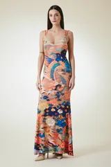 Vestido largo de corte al cuerpo con escote en V y breteles dobles finos. Presenta un estampado vibrante con motivos orientales, incluyendo aves y elementos florales en tonos naranja, azul y amarillo.