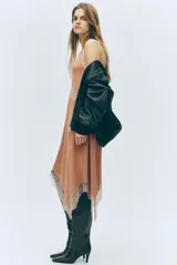 Vestido midi sin mangas de punto suave, con escote redondo y bajo asimétrico. Presenta detalles de encaje en las sisas, en la parte frontal y en el ruedo.