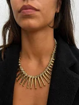Collar de diseño llamativo compuesto por una serie de dijes colgantes en forma de pez con acabado dorado texturizado, intercalados con pequeñas cuentas circulares de color blanco.