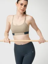Top deportivo de sujeción media y corte ajustado, color beige con banda inferior bicolor en azul oscuro. Confeccionado con tecnología Aloe Vera.