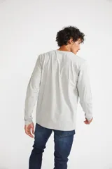 Remera de manga larga color gris melange, con cuello redondo y estampado gráfico en blanco y negro de la ciudad de Nueva York en el frente.