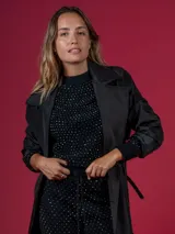 Trench negro con cuello solapa, doble botonadura y cinturón.