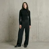 Pantalón de vestir negro con diseño de rayas diplomáticas blancas, corte recto y holgado, con bolsillos laterales.