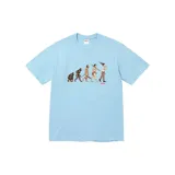 Remera de manga corta color celeste con estampado frontal que ilustra la evolución humana, con el logo de la marca Supreme en la parte inferior del diseño.