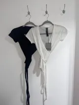 Top blanco de manga corta con escote cruzado y nudo en la cintura. Confeccionado en jersey de algodón.