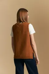 Chaleco tejido color azul, con escote en V, cierre frontal con botones y diseño de líneas verticales en relieve. Presenta terminaciones acanaladas en el ruedo y un borde ondulado en el escote.