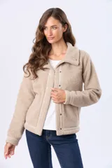Campera de sherpa color beige, con cuello camisero, cierre frontal con botones a presión y detalles de ribete en la solapa y puños.