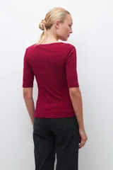 Remera verde de tejido canalé con cuello redondo y media manga. Tiene una abertura frontal con botones.