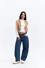 Chaleco de punto color beige, de corte corto y holgado. Presenta capucha, cierre frontal completo y terminaciones acanaladas en la cintura.