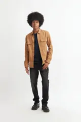 Camisa marrón de manga larga con cuello clásico, cierre frontal con botones, dos bolsillos con solapa abotonada en el pecho y puños abotonados.