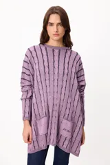 Sweater de punto con diseño de trenzas verticales en color lila con detalles en azul oscuro. Presenta un corte holgado, cuello redondo, mangas largas con puños ajustados y dos bolsillos frontales tipo parche con el logo de la marca bordado.