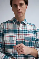 Camisa de manga larga a cuadros en tonos blanco, verde, azul y rojo. Tiene dos bolsillos en el pecho y cierre con botones.