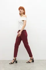 Pantalón de vestir color bordó, de corte recto, con bolsillos laterales y traseros. Se ajusta a la cintura con cinturón de cuero marrón.