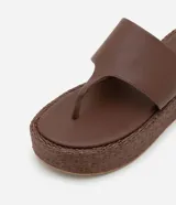 Sandalia femenina tipo ojota, color marrón, con plataforma mediana y suela en rafia.