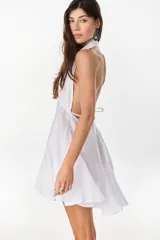 Vestido corto color amarillo de lino italiano, con escote halter cruzado en V pronunciado y cintura elastizada fruncida con falda amplia y voluminosa.