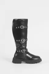 Bota bucanera de caña alta color negro, con suela track dentada y tres tiras horizontales con hebillas metálicas y ojales plateados.