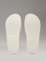 Ojotas Calvin Klein con tira ancha de tejido jacquard que presenta el logo de la marca en relieve. Poseen plantilla ergonómica moldeada con soporte para el arco y suela de EVA.