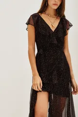 Vestido largo de gasa negra con estampado de puntos dorados, diseño cruzado con volados en el escote y falda, y forro interior corto.