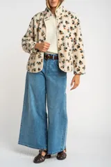 Campera de corderito con estampado floral, cuello alto y cierre frontal con botones a presión. Posee puños elásticos y un diseño de ajuste al cuerpo.