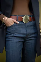 Cinturón de cuero color marrón con hebilla dorada de forma irregular.