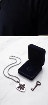 Collar de acero con cadena de eslabones trenzados y dije en forma de púa con diseño de flor de lis en relieve.