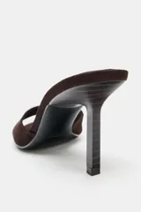 Sandalia tipo mule de tacón fino alto, confeccionada en serraje de color marrón con tira delantera ancha y punta redonda.