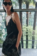 Top largo confeccionado en tejido de encaje con escote en pico y tirantes finos. Presenta una combinación de tejidos a tono con diseño sofisticado.