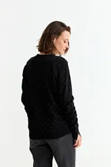 Sweater de manga larga, color negro, con cuello redondo y estampado de pequeños corazones dorados distribuidos por toda la prenda.