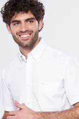 Camisa de manga corta color celeste claro, con cuello abotonado (button-down) y un bolsillo de parche en el pecho.