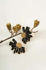 Aros con diseño de flor en color negro con bordes dorados y centro texturizado con pequeñas esferas doradas.