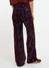 Pantalon de corte recto y tiro alto, confeccionado en tela con textura tipo pana o denim con un estampado abstracto en tonos marrones y azules.