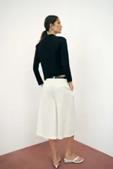 Chaqueta de punto negra de cuello redondo y manga larga, con bolsillos delanteros de parche y cierre frontal con alamares.