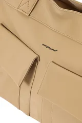 Cartera tipo shopper de poliuretano color beige, con dos bolsillos frontales con solapa, tirantes largos para el hombro y cordones ajustables en los laterales.
