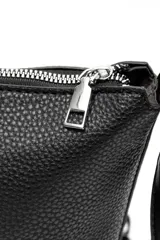 Bandolera de cuero sintético negro con textura granulada, cierre superior y correa ajustable.