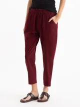 Pantalón de gabardina color bordó, de tiro medio con cintura elastizada y cordón regulable. Presenta calce relajado, corte recto y largo hasta los tobillos, con bolsillos laterales.