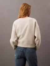 Buzo de cuello redondo color beige, confeccionado en suave tejido fleece. Presenta un logo de archivo de Calvin Klein bordado en el frente.