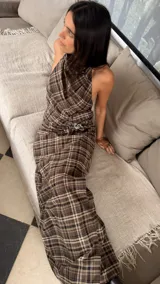 Vestido largo con escote halter y cuello buche, confeccionado en tela a cuadros. Presenta un tajo lateral, detalle de roseta y un pin de strass decorativo.