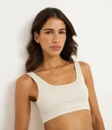 Top tipo bralette sin aros ni copas, color beige claro, con escote cuadrado y tirantes medianos. Presenta una banda inferior texturizada con doble línea horizontal.