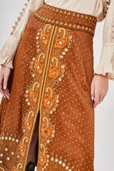 Falda larga marrón con estampado central de motivos florales en tonos naranjas y blancos, y pequeños puntos blancos distribuidos por toda la tela.