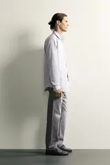 Jeans regular fit de mezclilla negra con efecto lavado, corte recto y tiro medio. Cuenta con diseño de cinco bolsillos y cierre frontal con cremallera y botón.