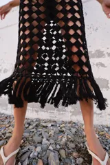 Vestido midi de crochet negro, sin mangas, con escote redondo y bajo terminado en flecos.