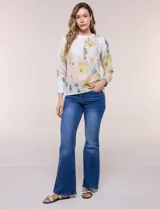 Blusa de silueta holgada y corte recto con caída fluida, escote redondo y mangas largas con puños anchos estructurados, con estampado floral en tonos pasteles sobre fondo blanco.