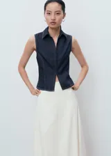 Top sin mangas estilo chaleco confeccionado en tejido de algodón y lino, con cuello solapa, cierre frontal con cremallera y costuras en contraste.